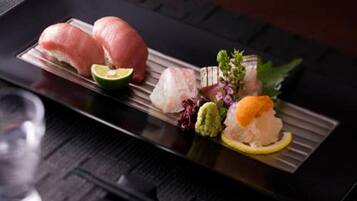 A sushi platter with various types of fish and garnishes on a rectangular plate.