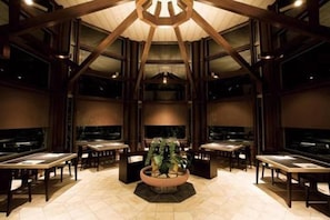 A spacious lobby with a central plant, multiple tables, and a high ceiling with wooden beams. - OyadoThe Earth (Toba)