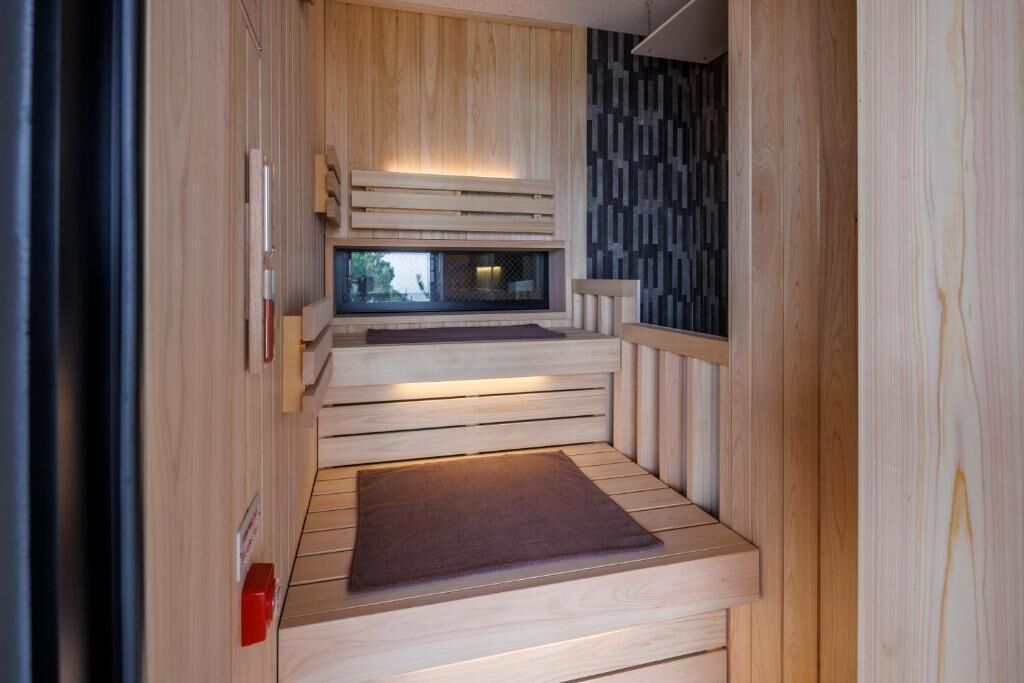 A sauna room with wooden walls, a bench, and a window.