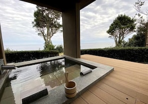 A hot tub with a wooden deck, surrounded by trees and a view of the sea. - OyadoThe Earth (Toba)