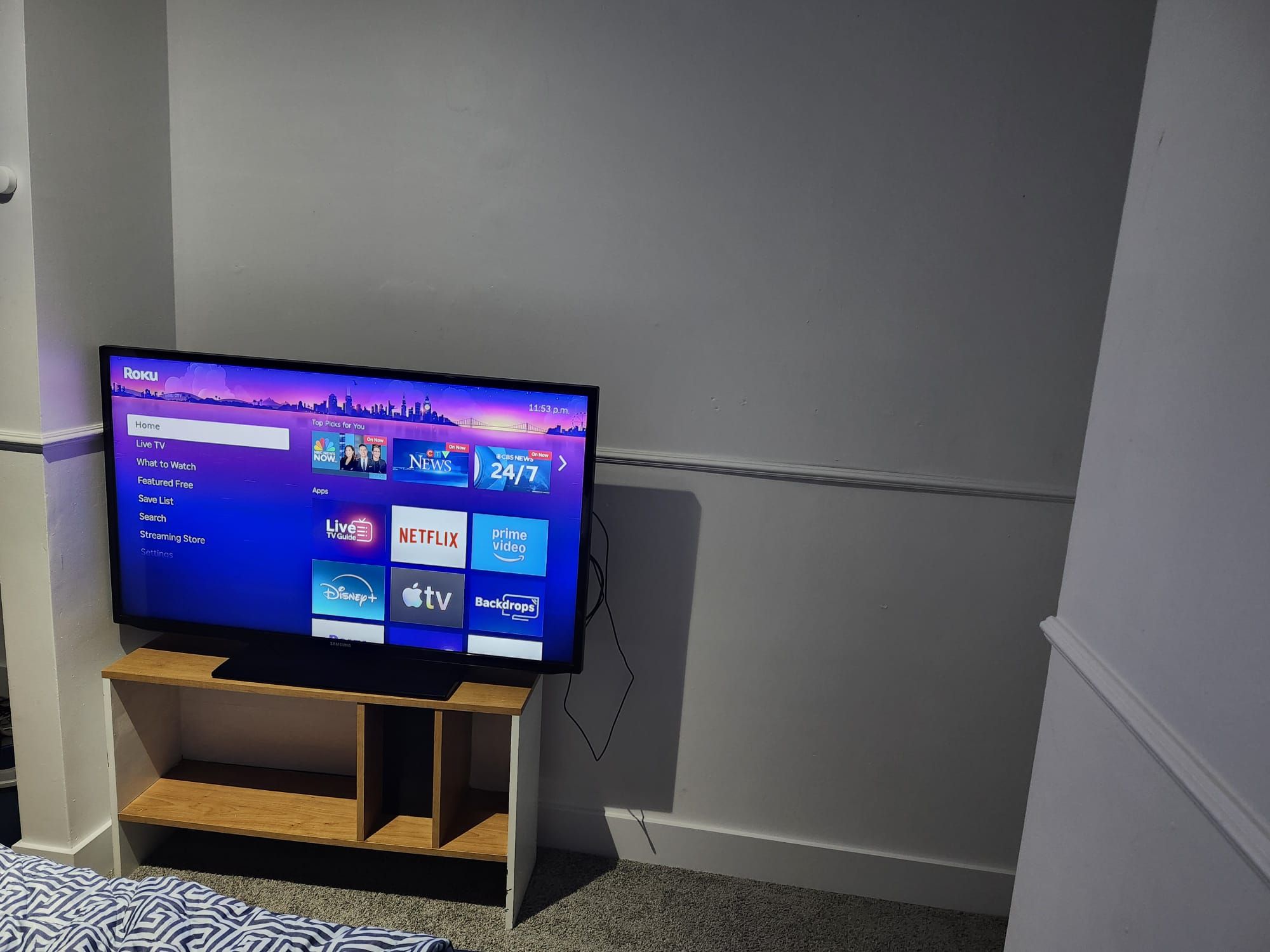 A television on a wooden stand in a room with a white wall and carpet.