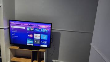 A television on a wooden stand in a room with a white wall and carpet.