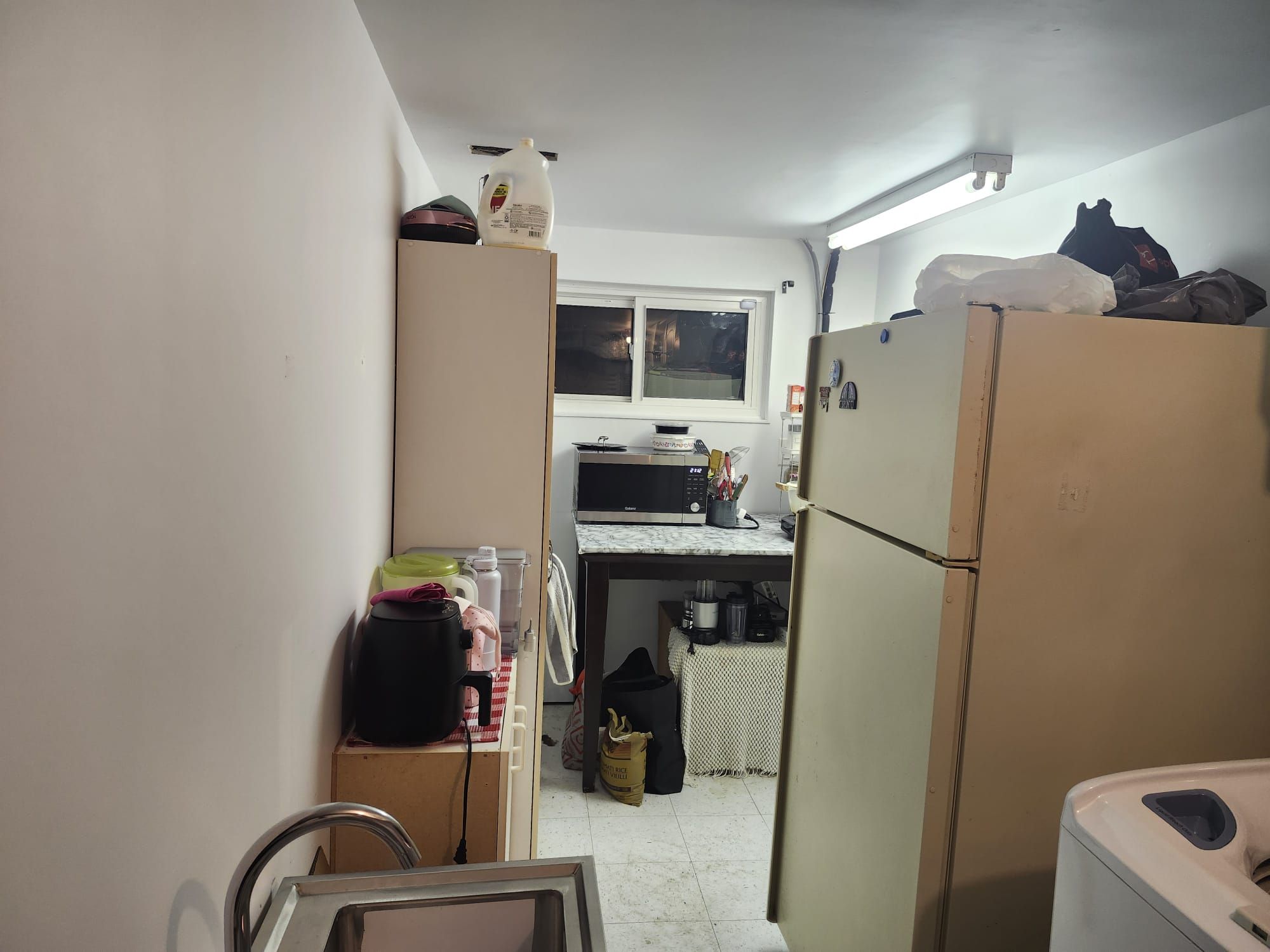 A compact kitchen with a refrigerator, microwave, and a small table.