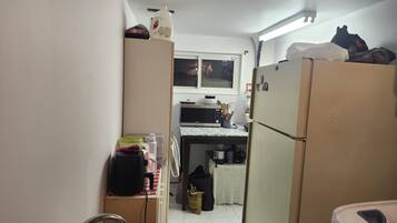 A compact kitchen with a refrigerator, microwave, and a small table.