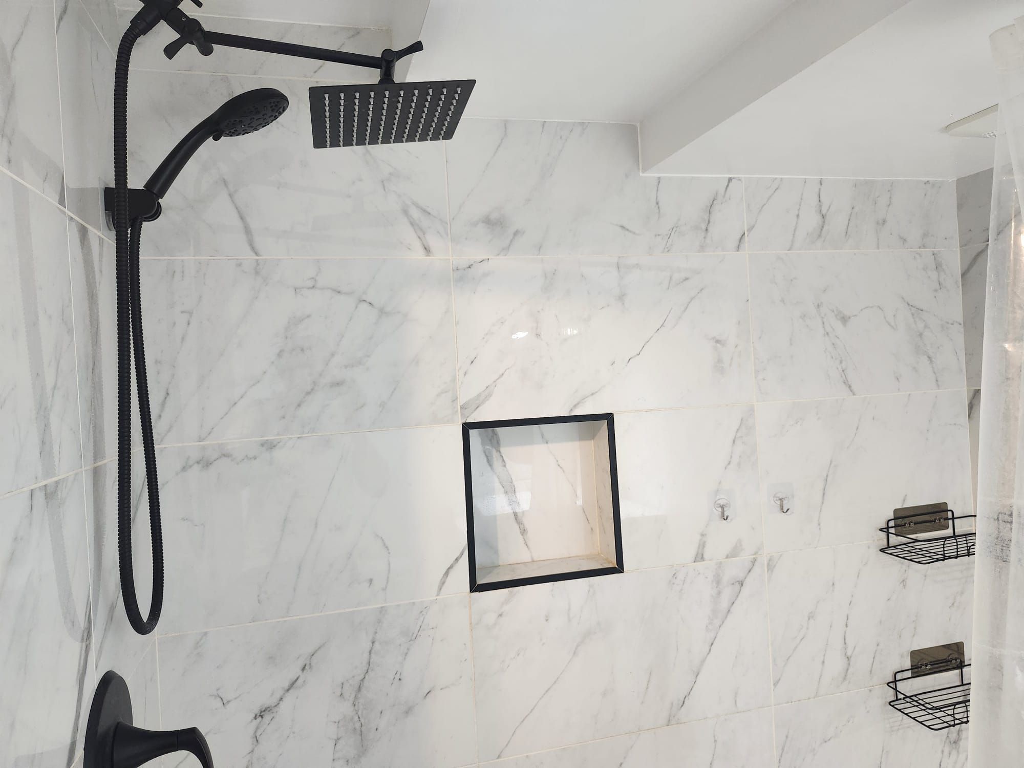 A bathroom with a shower, a towel rack, and a framed picture on the wall.