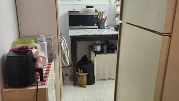 Cocina compacta con refrigerador, microondas y ventana sobre el fregadero.