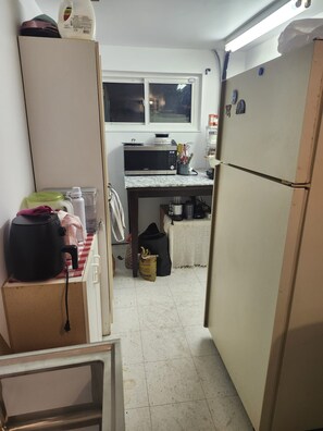 Cocina compacta con refrigerador, microondas y ventana sobre el fregadero.