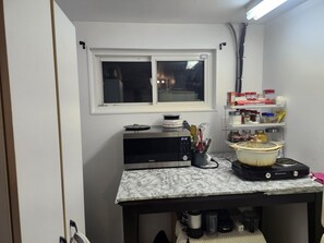 A compact kitchen with a microwave, toaster, and a pot on the counter.
