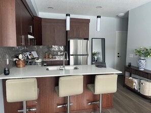 A modern kitchen with a central island, stainless steel appliances, and a large mirror.