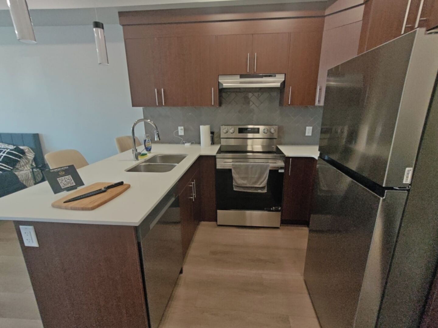 A compact kitchen with a stainless steel refrigerator, oven, and sink.
