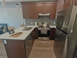 A compact kitchen with a stainless steel refrigerator, oven, and sink.