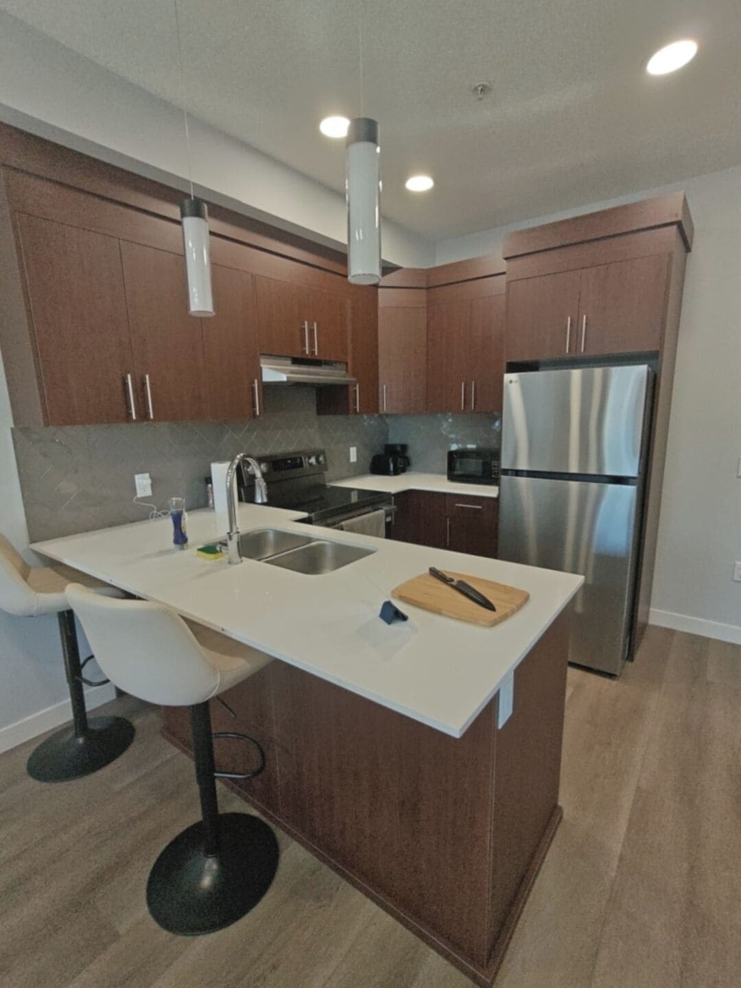 A modern kitchen with a central island, stainless steel appliances, and wooden cabinetry.
