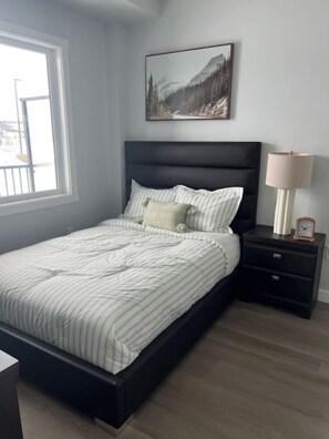 Un dormitorio con una cama, una mesita de noche, una lámpara y un cuadro en la pared.