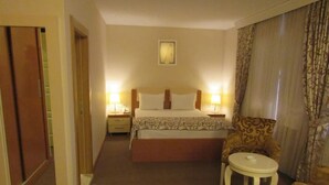 Une chambre d’hôtel avec un lit, des tables de chevet, une chaise et une petite table.