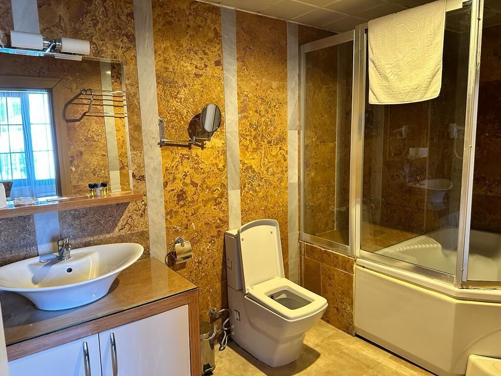 A bathroom with a sink, toilet, and glass shower enclosure.