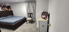 Una habitación de hotel con cama, una silla, un escritorio y un armario.