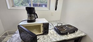 A kitchen with a microwave, toaster oven, and coffee maker on a marble countertop.