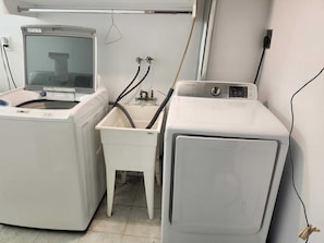 A laundry area with a washing machine, a dryer, and a small sink with hoses.