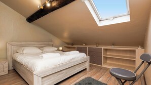Ein Schlafzimmer mit Schlafgalerie, einem Bett, einem Schreibtisch und einem Sessel.