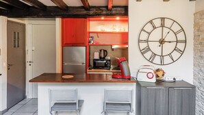 Eine Küche mit einer großen Wanduhr, einem Kühlschrank, einer Kaffeemaschine und einem Radio.
