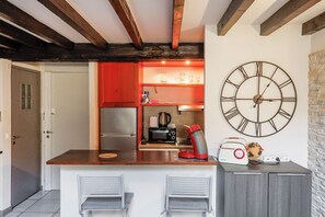 A kitchen with a large wall clock, a refrigerator, a coffee maker, and a radio. - Upstays Lions Duplex 45m² Suquet Port (Cannes)