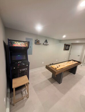 A room with a pool table, a foosball table, and a video game console.
