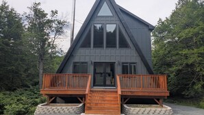 A modern, triangular-shaped building with a wooden deck and a central entrance. - Charming 3-bedroom chalet in marvelous Livingston Manor with a majestic Stream (Livingston Manor)