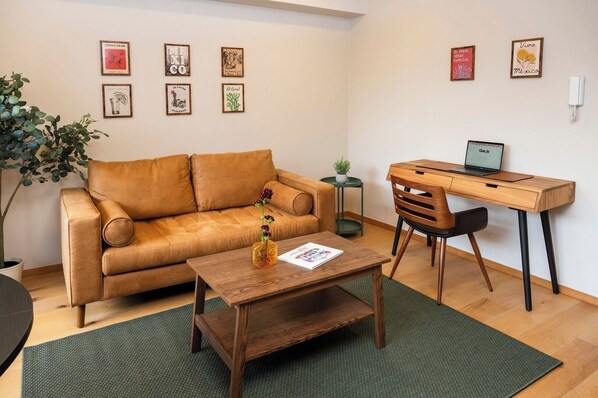 A furnished living room with a sofa, coffee table, desk, and laptop. - Contemporary Escape in Roma Norte (Mexico City)