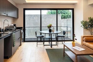 A modern kitchen with a dining area, a sofa, and a view of the outdoors. - Contemporary Escape in Roma Norte (Mexico City)
