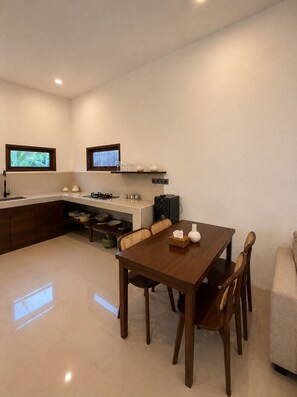 A modern kitchen with a dining area, built-in appliances, and a large window.