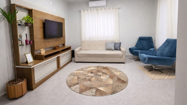 A living room with a TV, sofa, blue chairs, and a patterned rug.