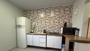 A compact kitchen with a refrigerator, microwave, sink, and wooden countertop.