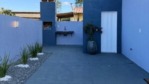 A modern building with a flat roof, a white door, and a small outdoor seating area.