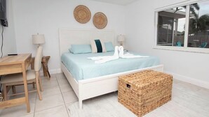 Una camera da letto con un letto, comodini, una scrivania, una sedia, un cesto in vimini e una finestra con vista.