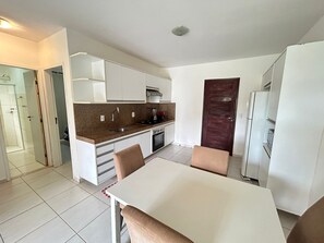 Une cuisine de taille réduite avec des meubles blancs, un plan de travail en granit, un four encastré et un réfrigérateur.