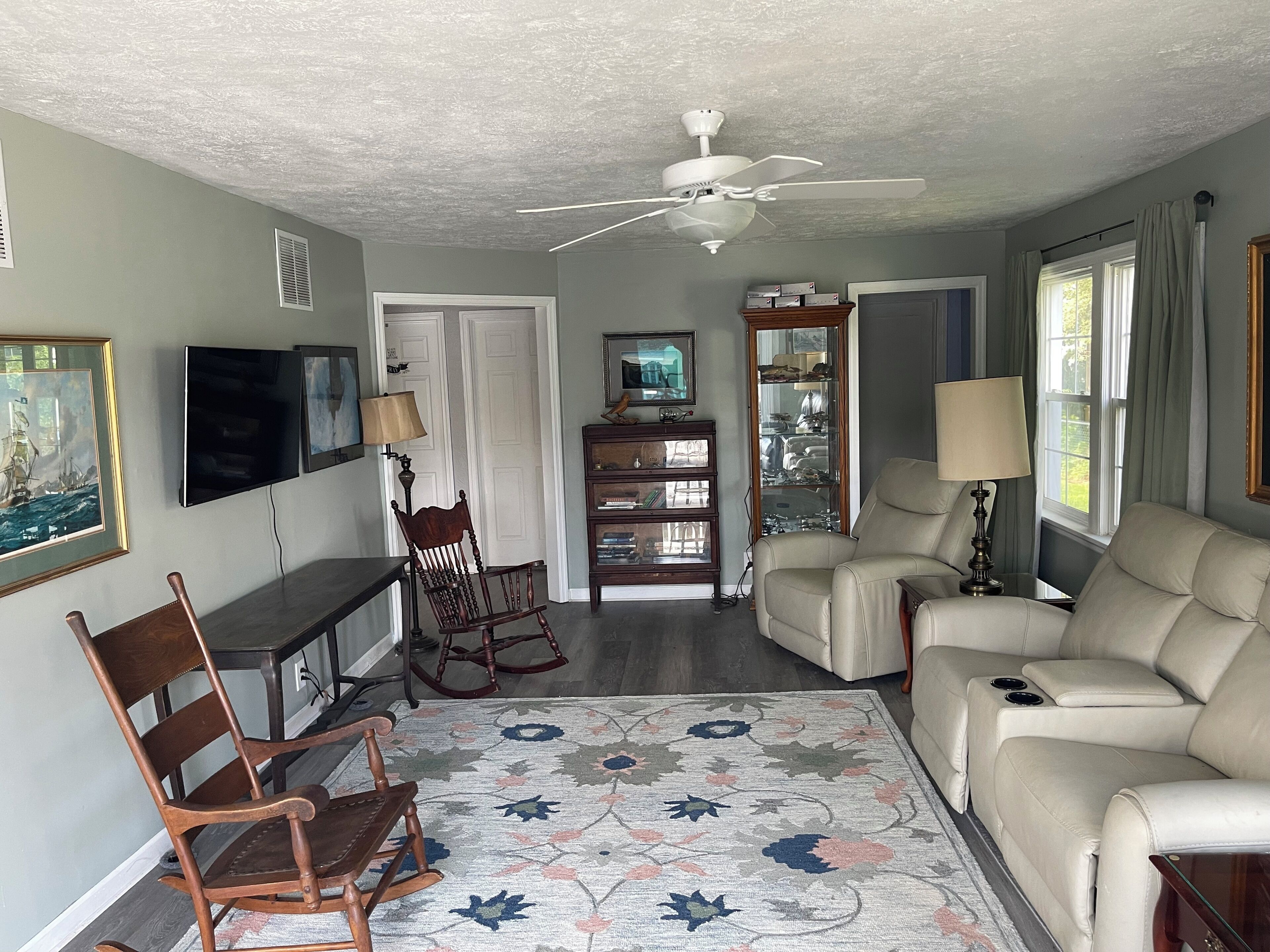 A living room with a ceiling fan, a television, a rocking chair, a sofa, a coffee table, and a patterned rug.