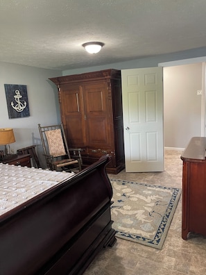 Une chambre à coucher avec un lit, une chaise, une armoire, une porte et un tapis.