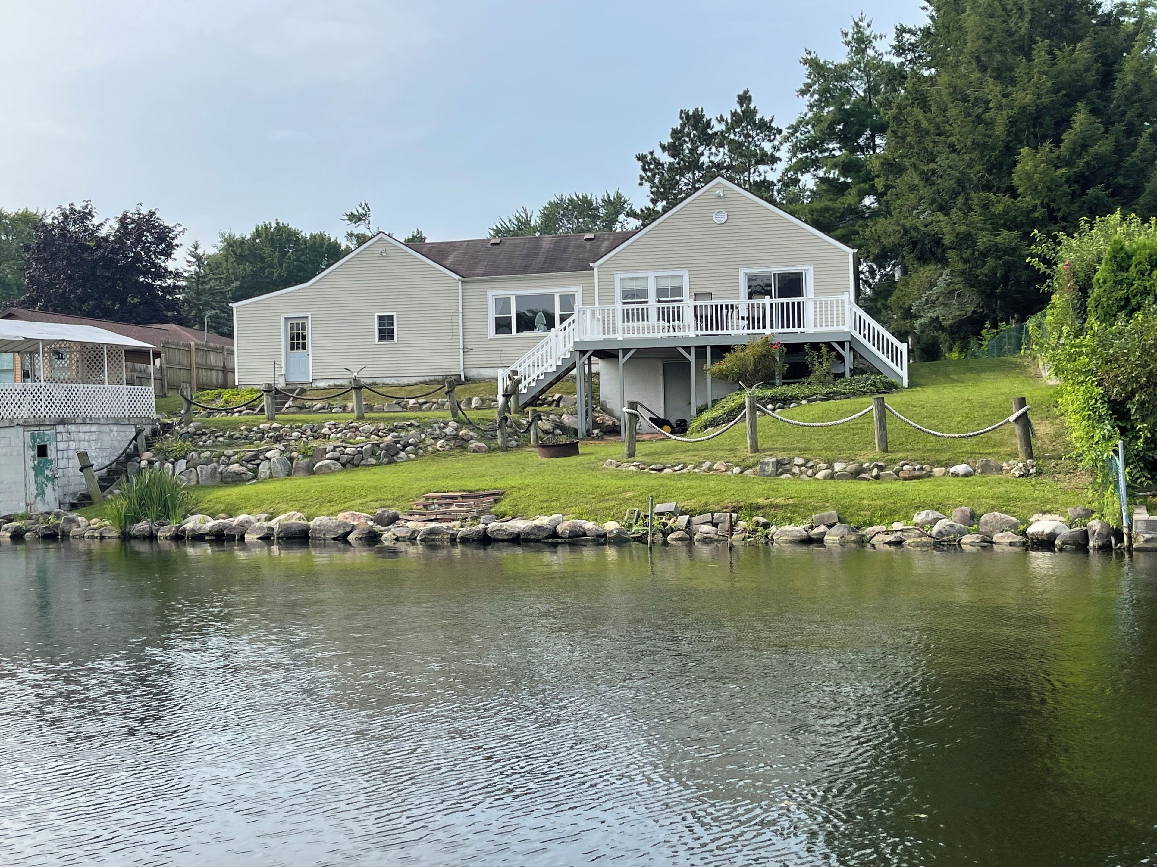 A two-story house with a balcony, a pond in front, and a wooden deck.