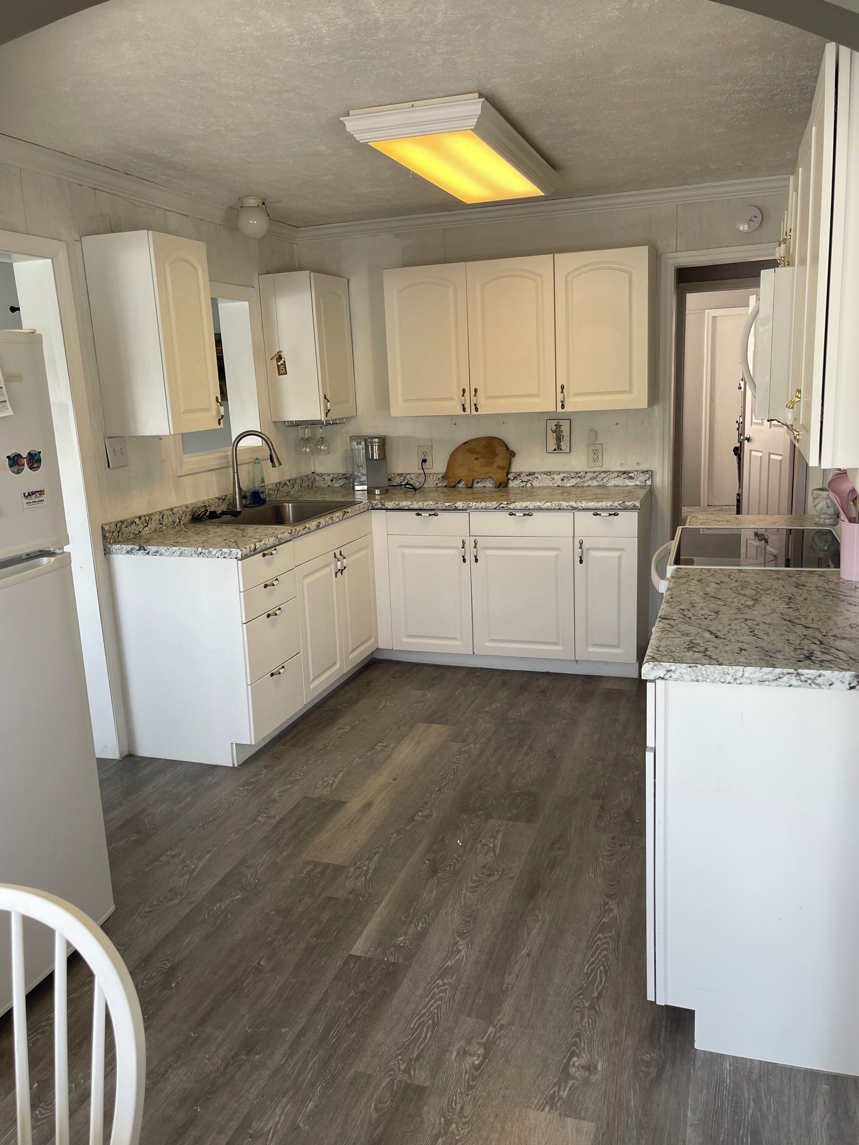A kitchen with white cabinets, a granite countertop, a wooden dining table, and a built-in oven.