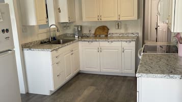 A kitchen with white cabinets, a granite countertop, a wooden dining table, and a built-in oven.