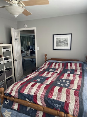 Une chambre à coucher avec un lit, un ventilateur de plafond, une armoire et un tableau encadré au mur.