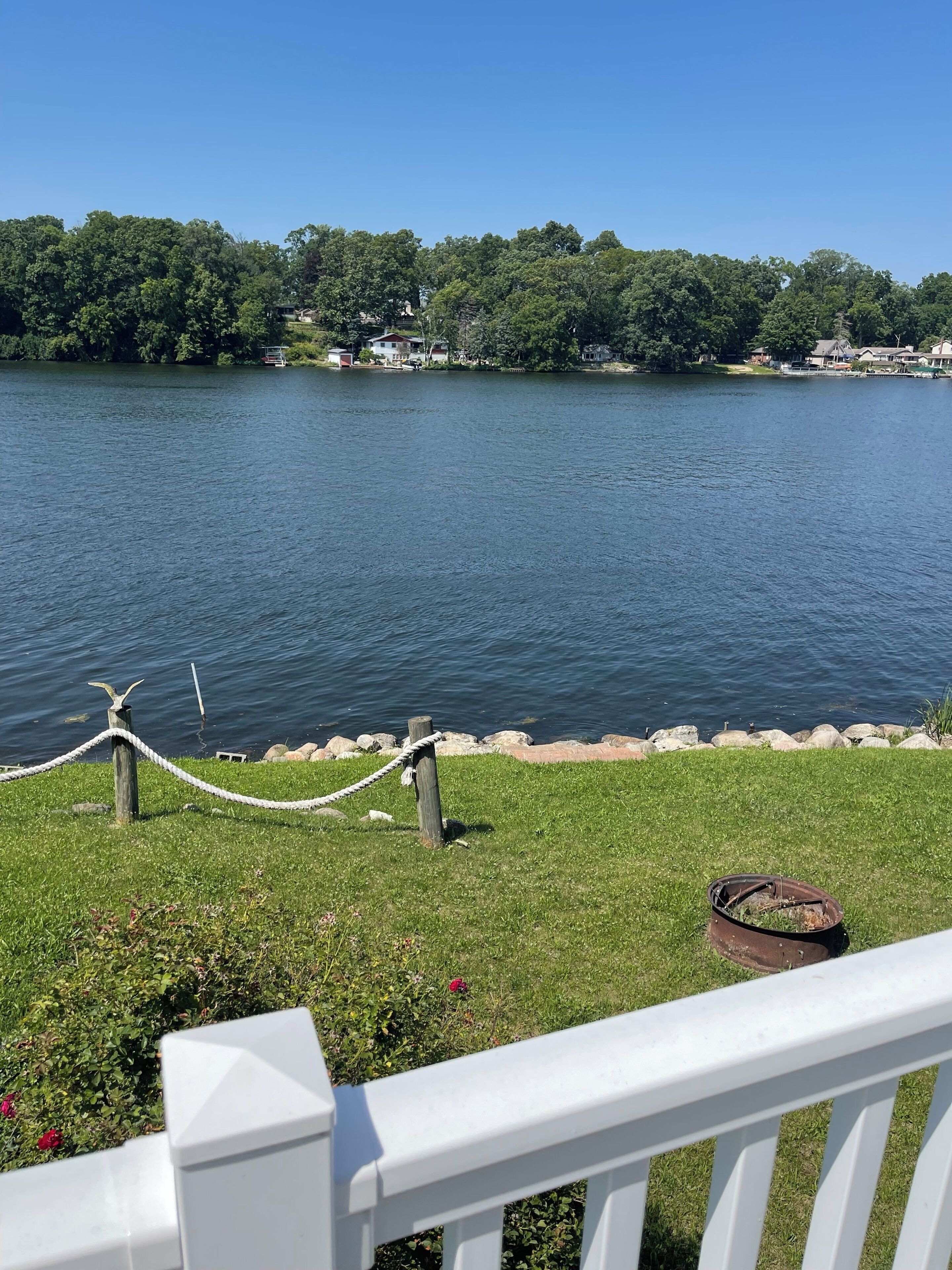 A lakeside view with a grassy area, a rope barrier, and a wooden dock.