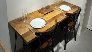 Un'area pranzo con un tavolo in legno, due sedie, un piatto appeso al muro e un bicchiere da vino.