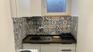 Cucina compatta con fornello, lavandino e finestra.