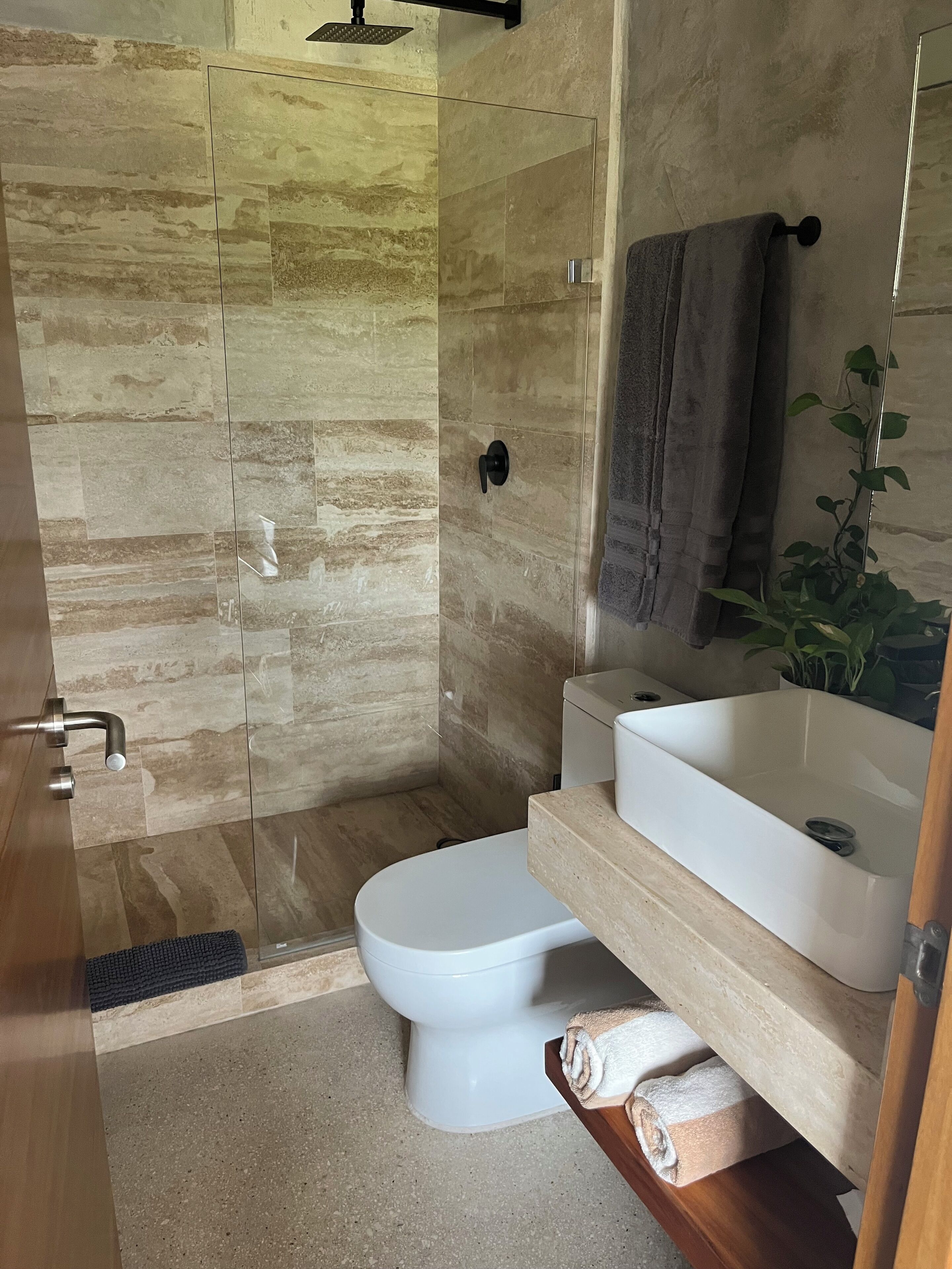 Un bagno moderno con box doccia in vetro, un water, un lavandino e un porta asciugamani.