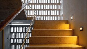 A staircase with a wooden handrail and a metal railing, leading to a lower level. - Donceles Plaza (Cancún)
