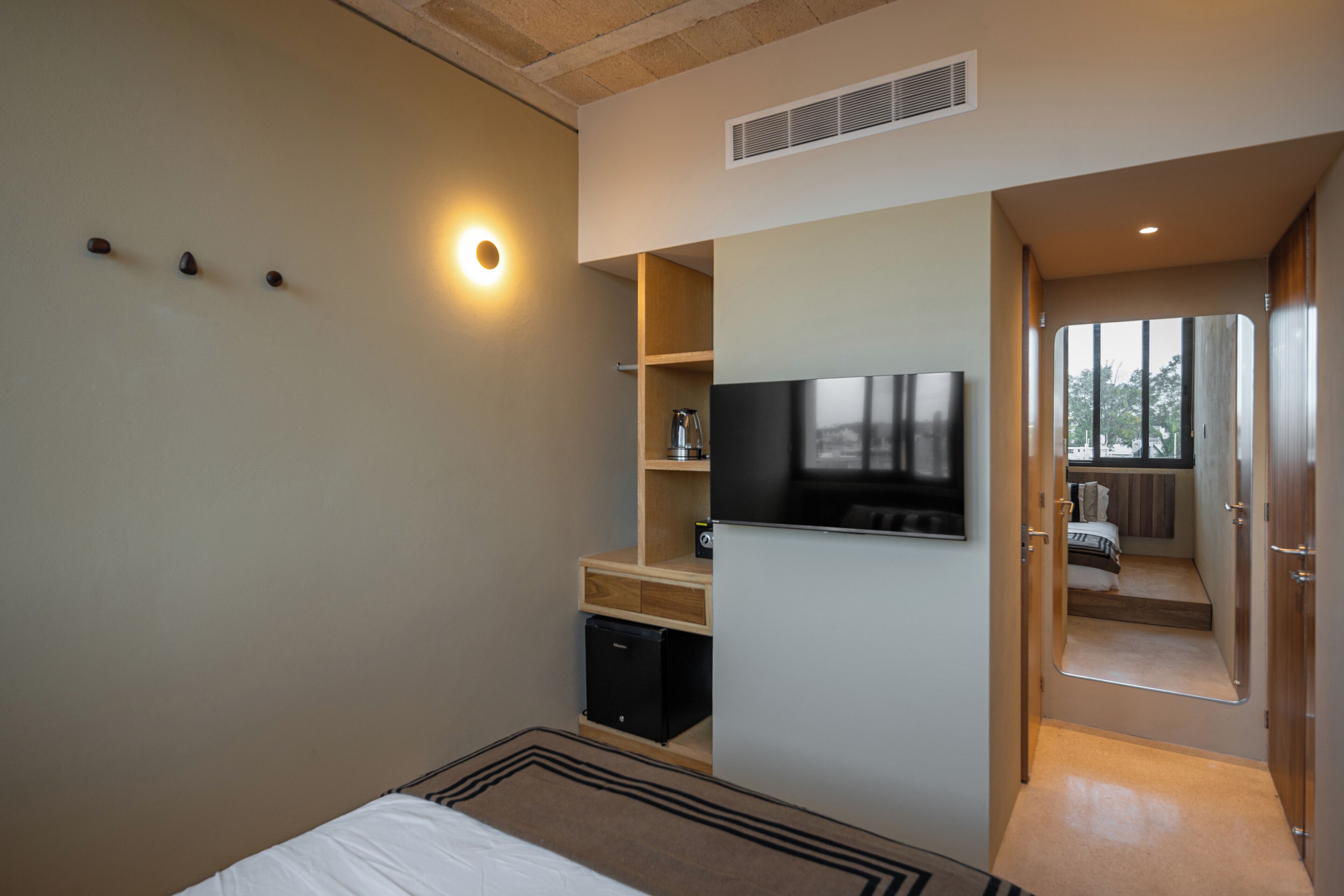 Ein Schlafzimmer mit einem Bett, einem Fernseher, einem Regal und einer Tür zu einem anderen Raum.