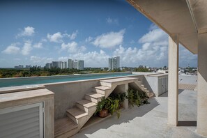 Una piscina en la azotea con vistas a un horizonte urbano, escalones de hormigón y plantas en macetas.