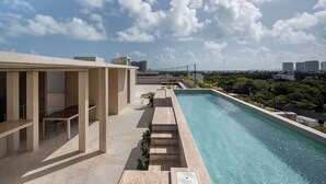 A rooftop pool with a clear view of the city skyline, a covered seating area, and a staircase leading to the pool. - Donceles Plaza (Cancún)