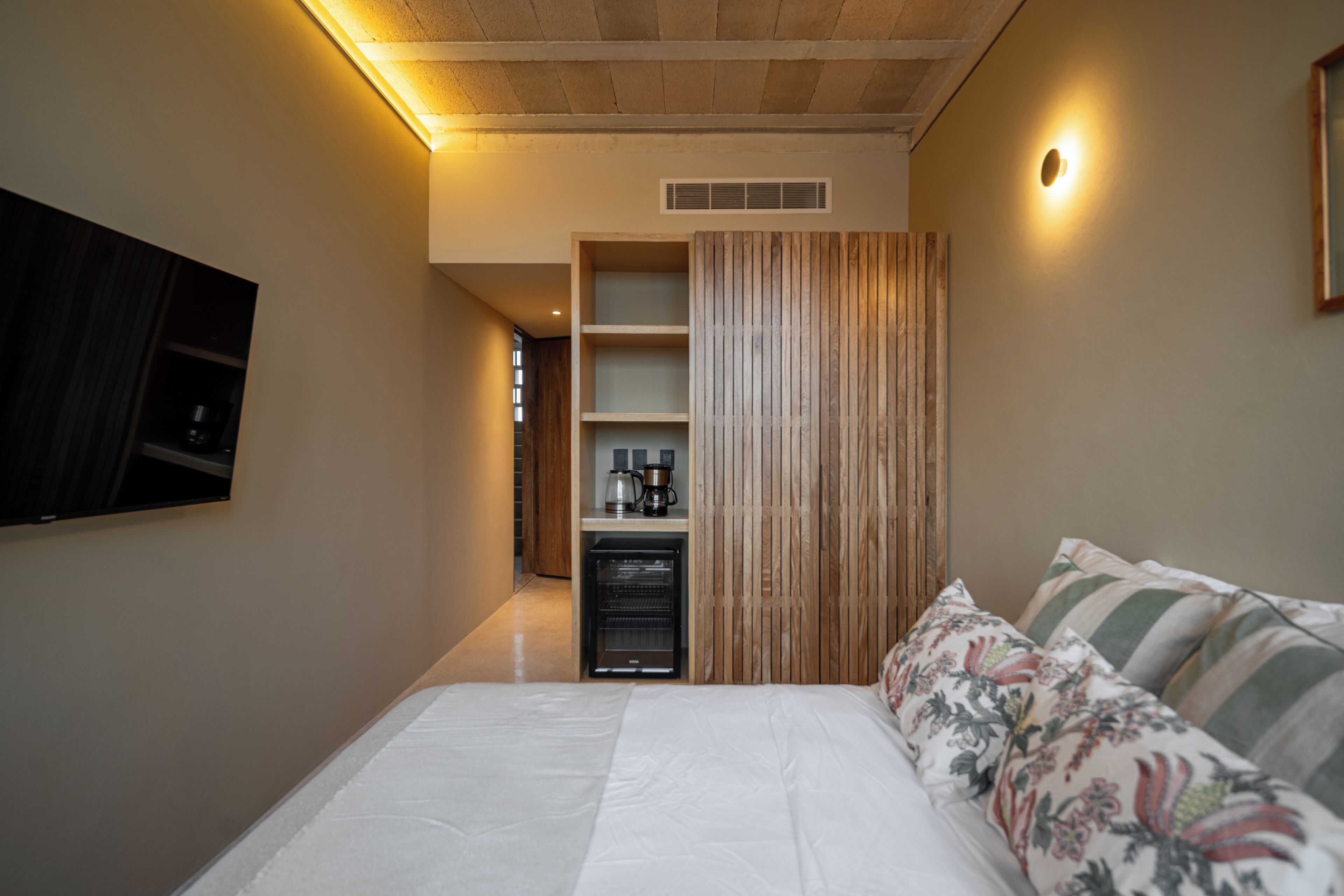 A bedroom with a bed, a television, a coffee machine, and a wardrobe.